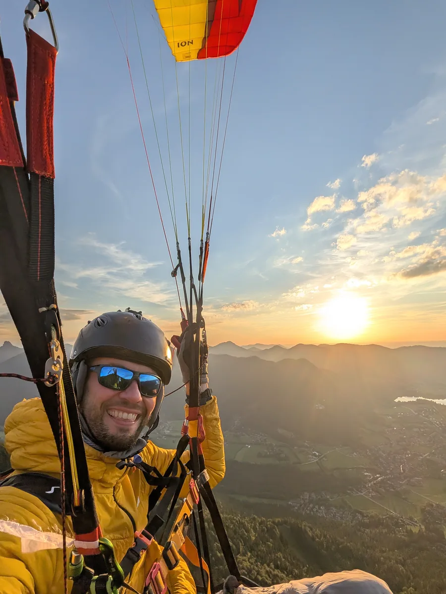 Maximilian Wäger im Gleitschirm bei Sonnenuntergang über dem Tegernsee